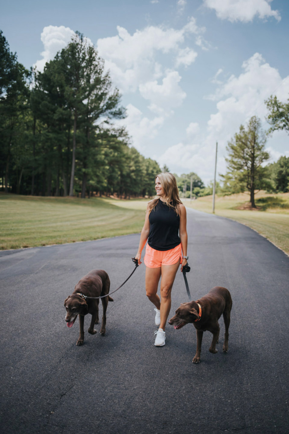 Jill Lewis walking her two chocolate lab dogs outside